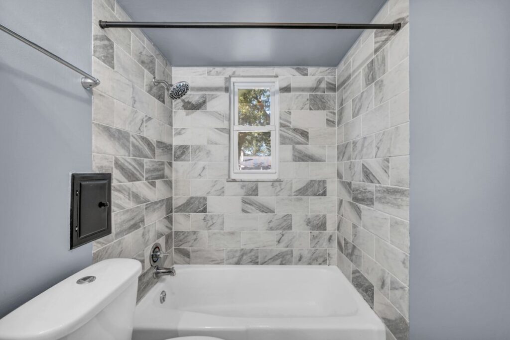 Renovated bathroom with marble wall tiles and a freestanding bathtub