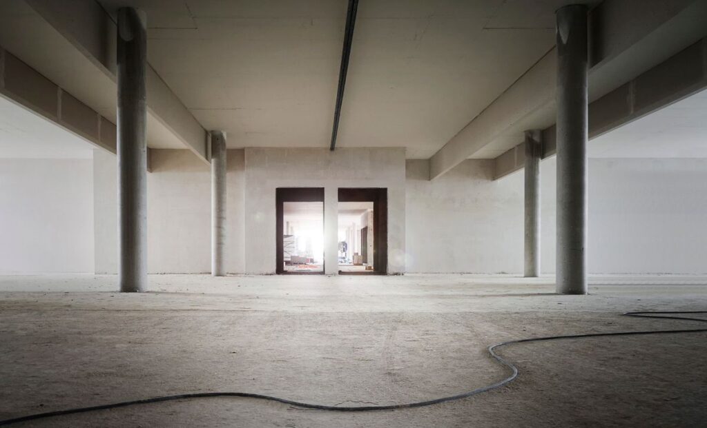 Empty commercial shell space with concrete columns and unfinished walls before a build-out