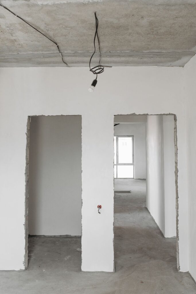 Apartment room stripped to plaster walls and exposed ceiling during a gut renovation